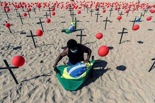 Een activist bindt een Braziliaanse vlag aan een van de kruizen op het strand van Copacabana in Rio de Janeiro, een eerbetoon aan de slachtoffers van de coronapandemie.