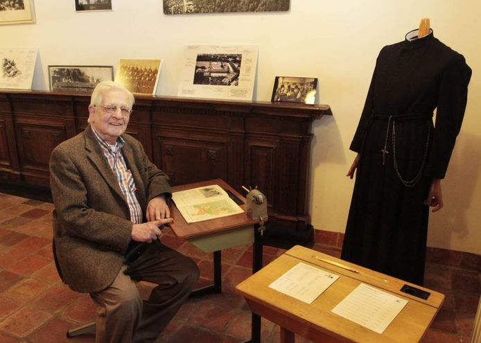 Broeder Adri Franken, conservator van het Wilhelmietenmuseum in Huijbergen, weer even in de schoolbanken met voor hem een aardrijkskundeboek uit 1928.
