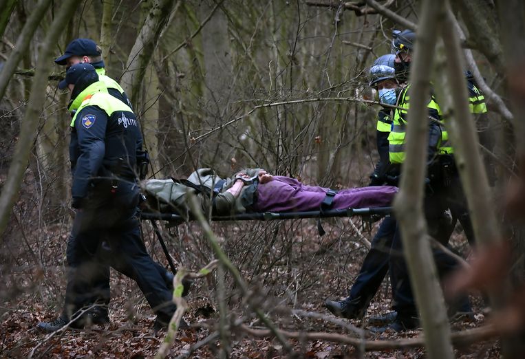Een uit de boom gehaalde demonstrant wordt geboeid op een brancard afgevoerd. Beeld Marcel van den Bergh / de Volkskrant