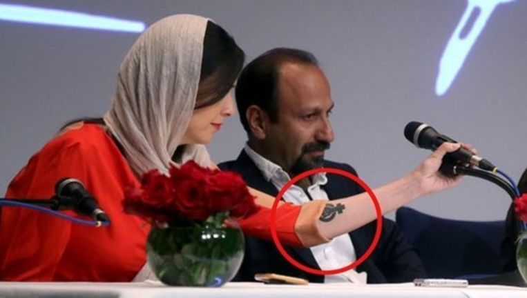 Taraneh Alidoosti reikte tijdens de persconferentie naar een microfoon, waarna de feministische tatoeage op haar arm zichtbaar werd. Beeld  