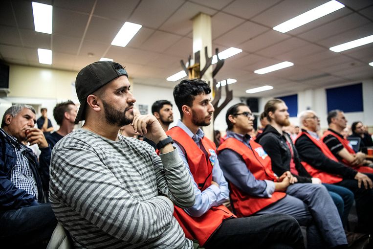 Inwoners, veelal van Marokkaanse komaf, van de wijk Hillesluis luisteren aandachtig naar woorvoerder FNV. Beeld Guus Dubbelman / de Volkskrant