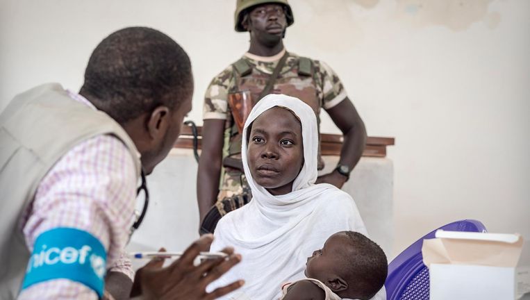 De arts Ernest Okoli van Unicef praat met een patiënt in de Noord-Nigeriaanse deelstaat Borno, waar de terreurgroep Boko Haram actief is. Een regeringssoldaat houdt de wacht. Beeld Sven Torfinn