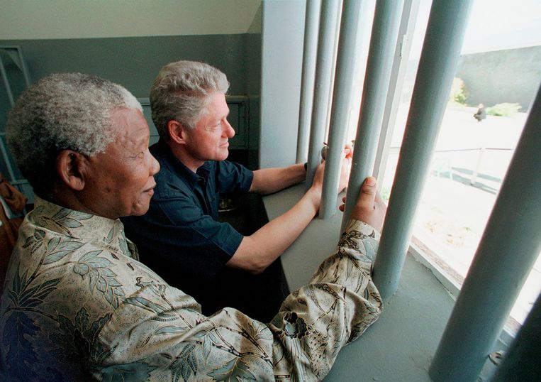 Nelson Mandela (links) en voormalig president Bill Clinton bezoeken de cel waar Mandela gevangen zat. Beeld AP