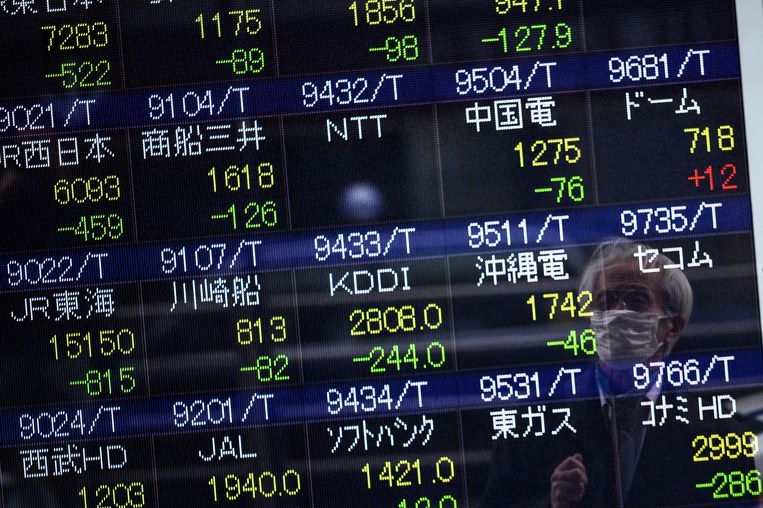 Een man bekijkt de cijfers van de beurs in Tokio. Beeld AFP