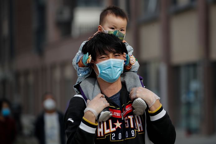 En man en zijn kindje met mondmaskers in Peking vandaag.