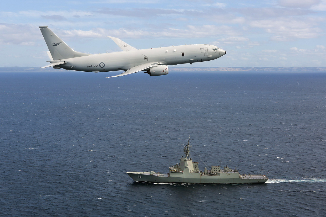 Een vliegtuig van de Australische luchtmacht vliegt over een luchtverdedigingsschip van de marine.