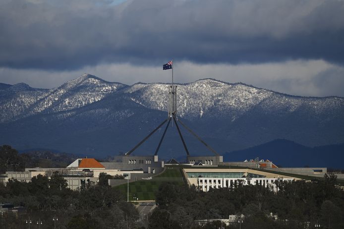 Het Parliament House in de Australische hoofdstad Canberra met besneeuwd bergen op de achtergrond.