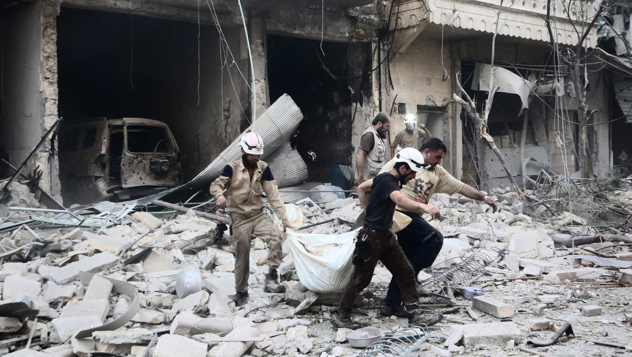 Leden van de Syrian Civil Defense, beter bekend als de White Helmets, halen een lijk van onder het puin in Aleppo. Beeld Belgaimage