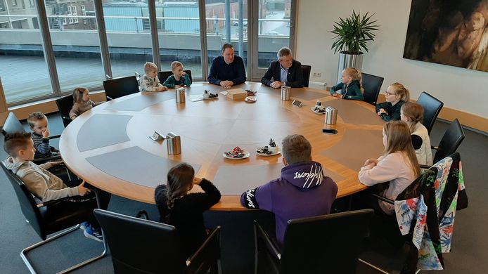 In de vergaderkamer van B. en W. spreekt wethouder Wijdeven met de leerlingen van De Kiem. Naast hem de verkeersambtenaar.