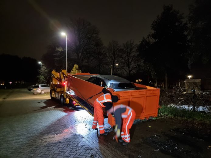 Une Mercedes électrique est placée dans un bac de trempage après avoir pris feu.  La société de récupération y verse ensuite de l'eau pour refroidir complètement la voiture.