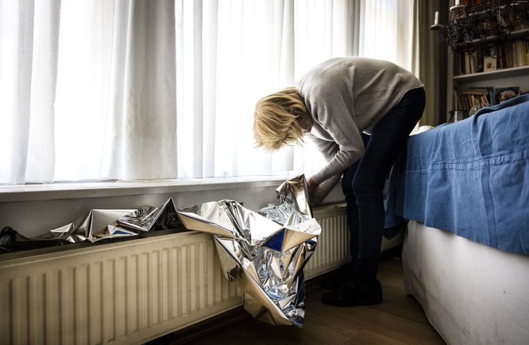 Het plaatsen van radiatorfolie bij een radiator om energie te besparen. Volgens directeur Arjan Vliegenthart van het Nibud zijn veel mensen actief aan de slag gegaan met besparen. Beeld ANP /  RAMON VAN FLYMEN