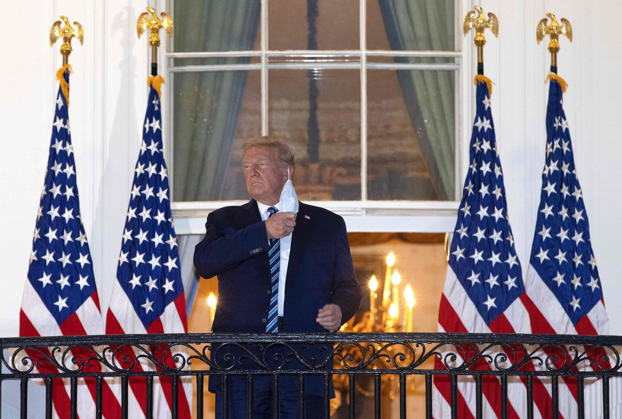 De Amerikaanse president Donald Trump verwijdert zijn mondkapje op het balkon van het Witte Huis. Beeld AFP