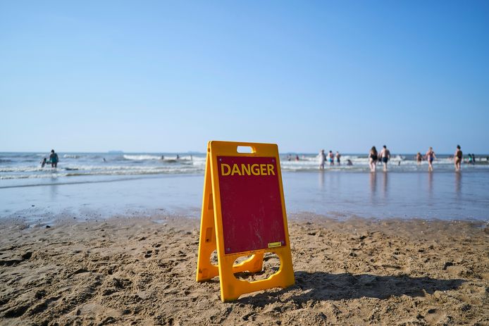 Een waarschuwingsbord op het Scheveningse strand, vanwege harde wind en gevaarlijke stroming.