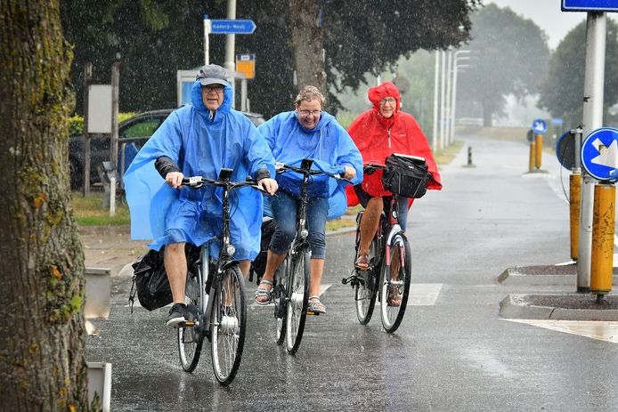 Fietsers in de eerste grote regenbui na lange droogte. Drentse toeristen uit Smilde op fietsvakantie in Twente.