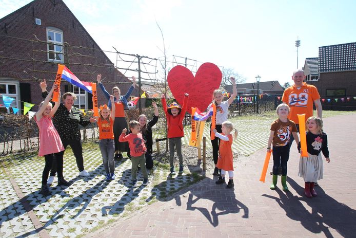 Inwoners en hun kinderen uit Oostelbeers die met een zelfgemaakte vlaggenslinger een stil protest voeren tegen de voorgenomen sluiting van hun basisschool De Beerze.