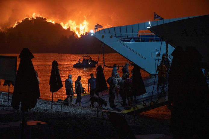 Bewoners van Evia worden per ferry geëvacueerd terwijl de branden in de achtergrond woeden.