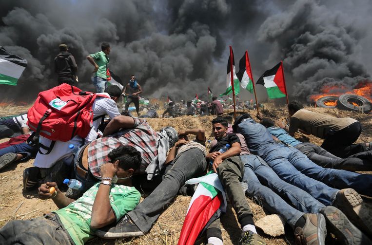 Palestijnse demonstranten kruipen bij elkaar tijdens de confrontatie met Israëlische veiligheidstroepen.  Beeld Photo News