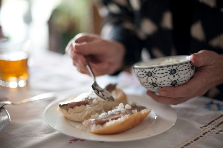 Typical Dutch lunch dish: raw herring and onions on a white bun. Beeld Getty Images