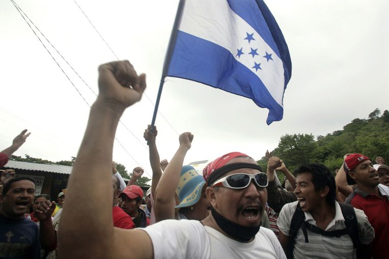 Aanhangers van de verdreven Hondurese president Manuel Zelaya schreeuwen protestleuzen terwijl ze een wegblokkade opwerpen in Las Manos, een grensplaats in Honduras. (Reuters) Beeld 