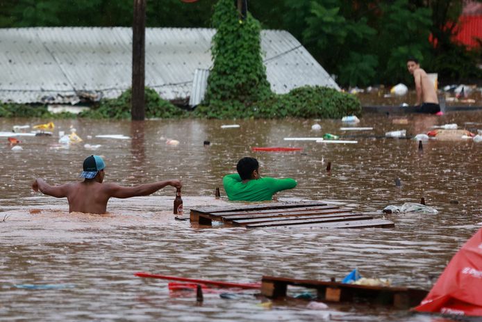 Mense waden door een overstroomd gebied in de plaats Encantado in de Braziliaanse deelstaat Rio Grande do Sul.