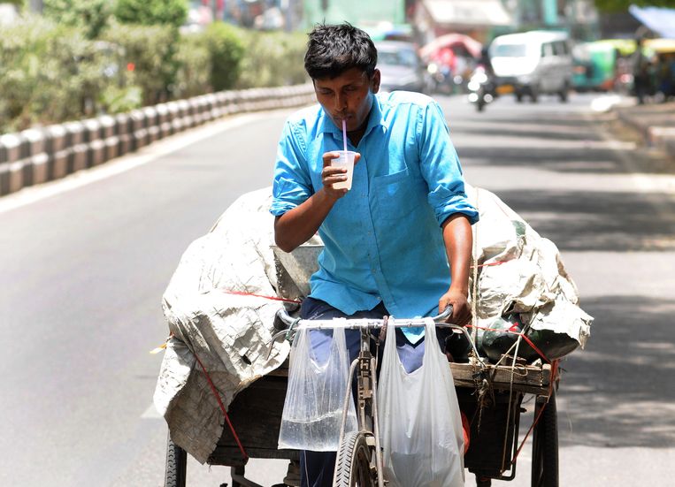 Een fruitverkoper in New Dehli drinkt vocht om het werken in de hitte (48 graden met zon) vol te kunnen houden. Beeld EPA