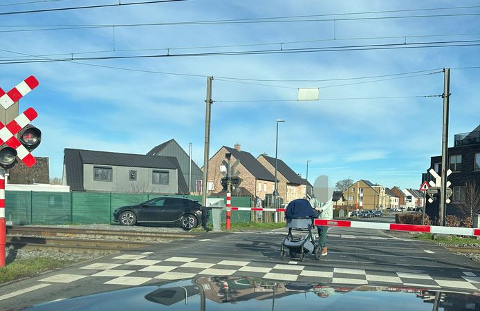 Een vrouw kruist met haar buggy de gesloten spoorwegovergang in Wetteren. Infrabel noemt dit waanzinnig gedrag.