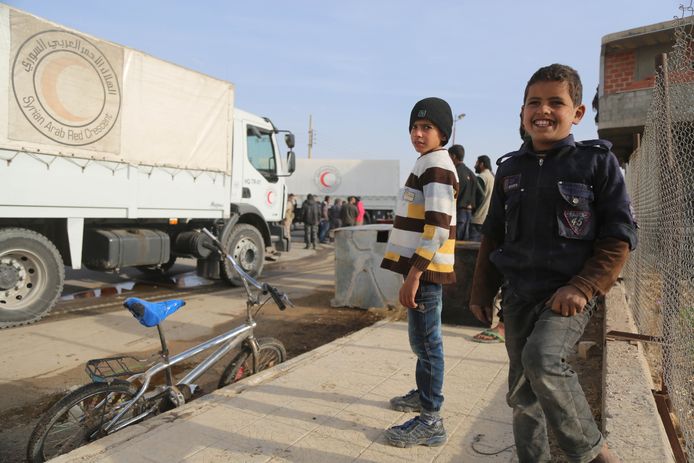 Syrische kinderen bij voertuigen van de Internationale Halve Maan tijdens een levering van humanitaire hulpt in al-Nashabia.