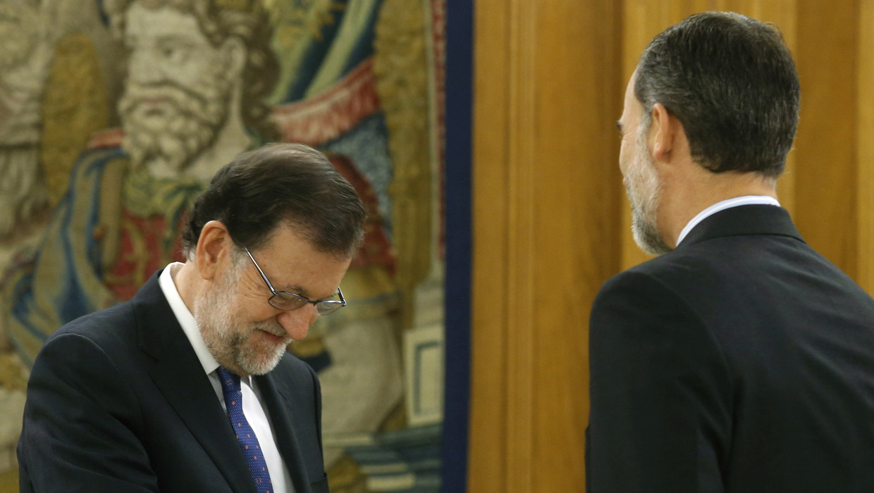 Premier Rajoy buigt voor koning Felipe VI, vanochtend. Beeld Getty Images