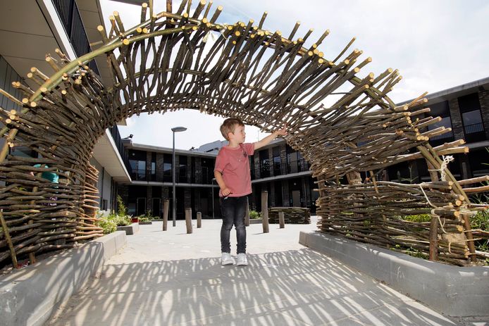 Een jongen bekijkt vol bewondering de stokkentunnel, gemaakt van boomtakken.  In De Vleer zijn basissschool De Hofstee , basisschool De Springplank en kinderdagverblijf Kober gevestigd.