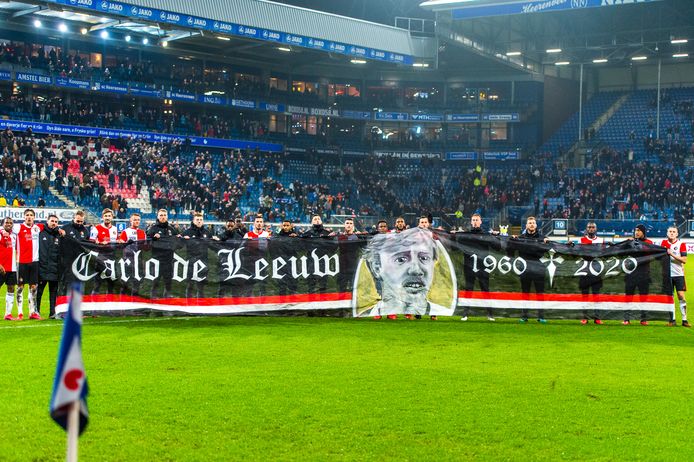 De selectie van Feyenoord met het spandoek van de donderdag overleden Carlo de Leeuw.