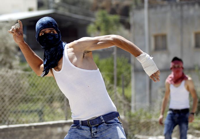 Een gemaskerde Palestijn gooit een steen naar de Israëlische grenspolitie tijdens een protest in Beit Jala. Archiefbeeld.