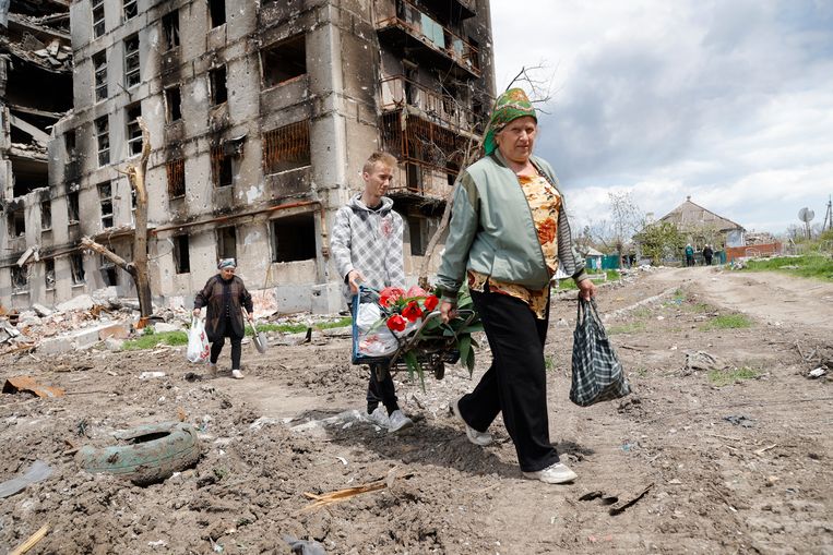 Oekraïense burgers wandelen langs uitgebrande gebouwen. Beeld AP