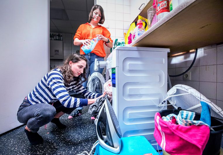 Michèle Brussé (l) vult met een medebewoonster van Huize Rood de leasewasmachine die de studentes 2,40 euro per maand per persoon kost. Beeld Raymond Rutting / de Volkskrant