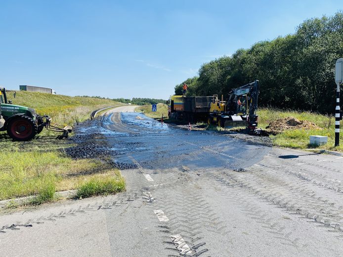 Een vrachtwagen en tractor ruimen het slib op.