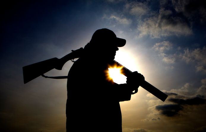 Een jager loopt met zijn wapen door het land. De dubbelloops is 'geknakt’ voor de veiligheid: die kan nu niet onbedoeld afgaan.