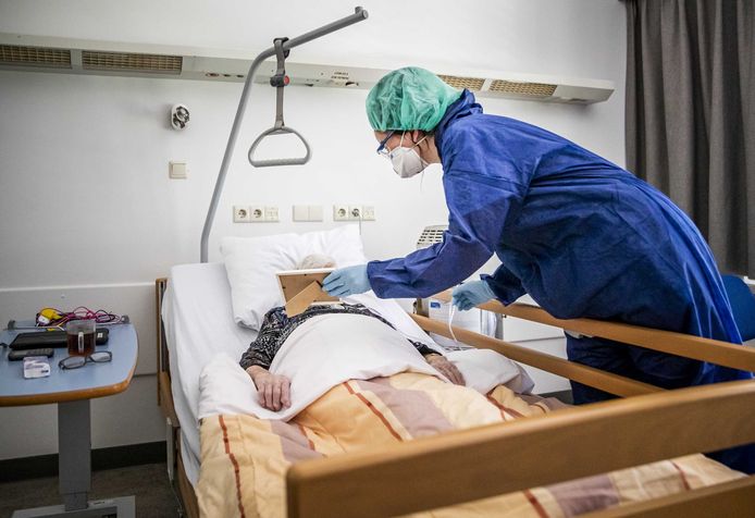 Een zorgmedewerker laat een familiefoto zien aan een coronapatient op een speciale cohort-afdeling in het Amphia ziekenhuis.