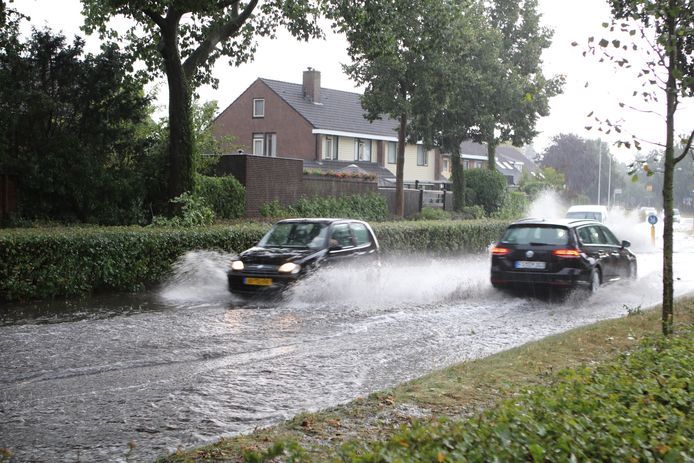 Auto's waden door het water op de Lunterseweg in Barneveld.