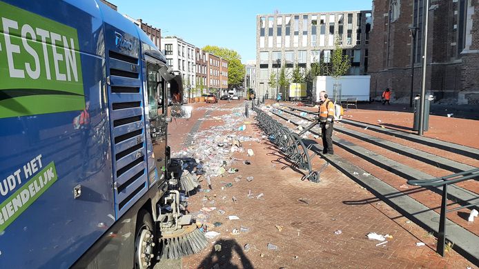 Aan de voet van de Eusebiuskerk in Arnhem wordt het plastic van Koningsdag bijeen geblazen, zodat de veegwagens het op kunnen zuigen.