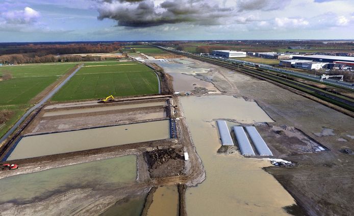 Het terrein van de nog aan te leggen golfbaan in Spijk. Op de voorgrond links een bassin waarin water wordt opgevangen. Rechts is de A15 te zien.