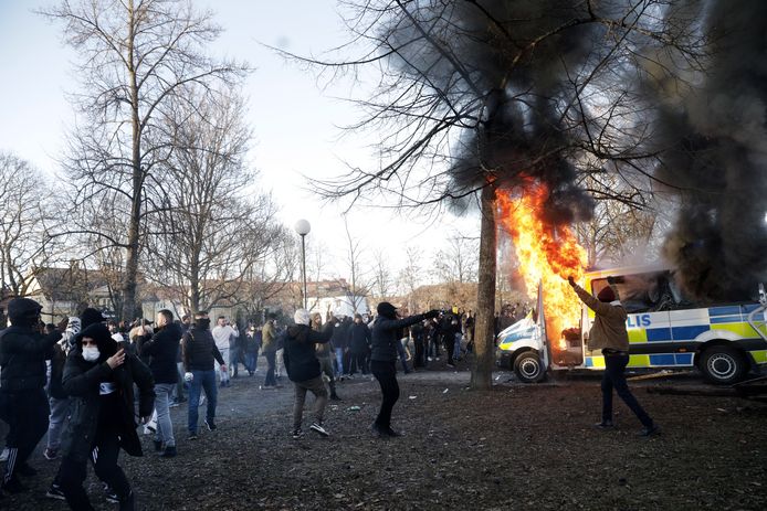Cheering counter-protesters at a torched police vehicle in Örebro on Good Friday.
