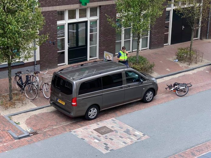 Een toezichthouder deelt een waarschuwing uit aan de bestuurder van een rouwauto in Zwolle. De wagen stond geparkeerd bij het Theodora Vos De Wael Huis vanwege een overleden cliënt.