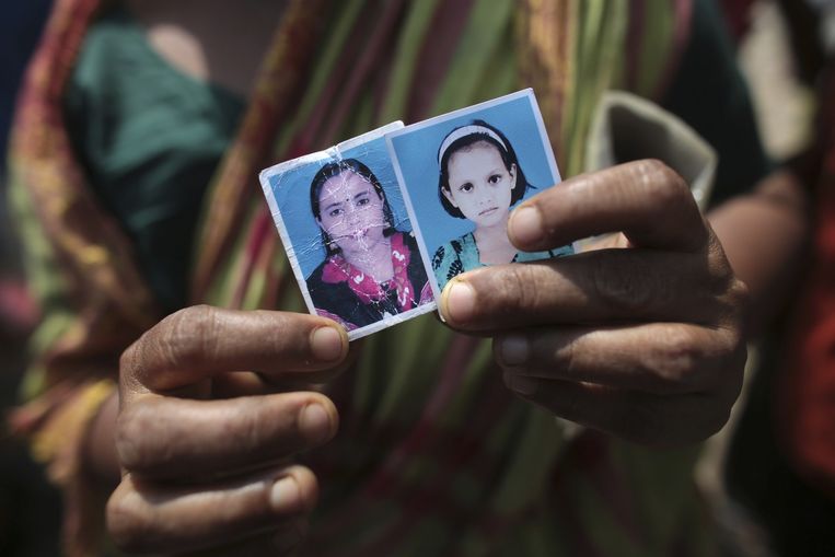Een vrouw toont foto's van haar dochter die is omgekomen bij de ramp met het Rana Plaza-complex in Bangladesh en haar kleindochter. Beeld Reuters