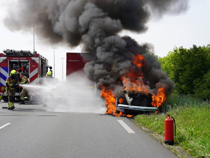 Inzittenden van oldtimer verlaten hun voertuig net op tijd, nadat ze uitstappen schieten de vlammen uit hun auto