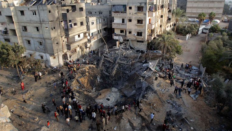 Palestijnen verzamelen zich rond een gebombardeerd huis in de Gazastrook Beeld REUTERS