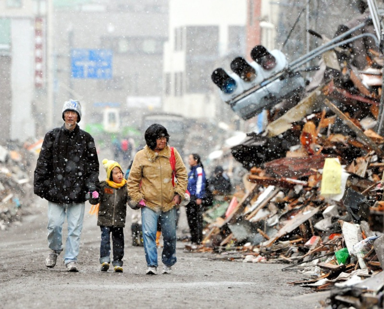 Een Japans gezin loopt door de verwoeste stad Kamaisi. Beeld epa