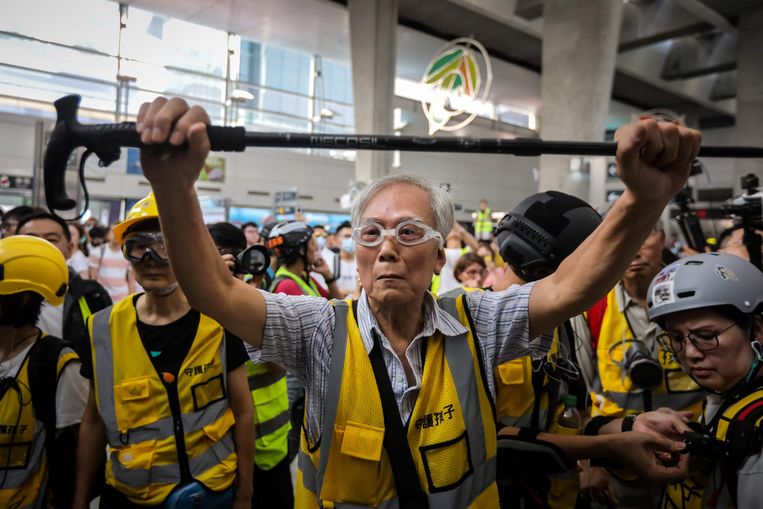 ‘Opa Wong’ gebruikt zijn wandelstok om politie en demonstranten in Hongkong te scheiden. De 85-jarige man is geregeld aanwezig bij protesten tegen de overheid. Beeld AFP
