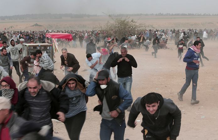 Palestijnse betogers rennen voor traangas tijdens confrontaties met Israëlische soldaten langs de grens tussen Gaza en Israël.
