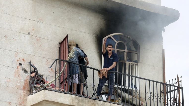 Een man bij zijn huis in Sanaa dat werd geraakt door een luchtaanval. Beeld reuters