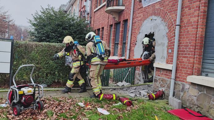 Brandweermannen halen het slachtoffer naar buiten.