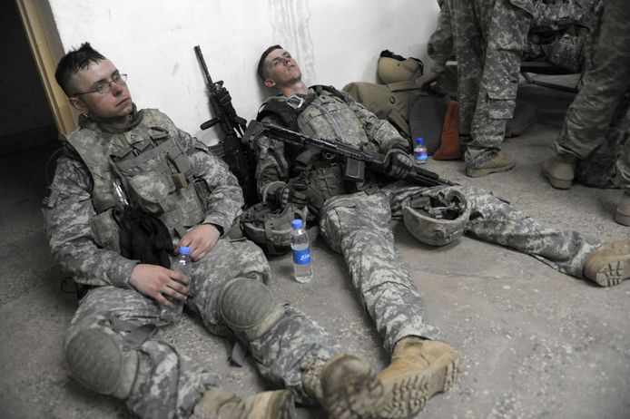 Archieffoto: twee Amerikaanse soldaten liggen na een missie uitgeput op de grond in Afghanistan.